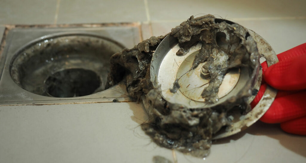 image of shower person holding shower drain to find the cause of a bad smell