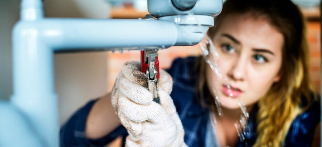 woman trying to fix plumbing issues her self instead of hiring a plumber