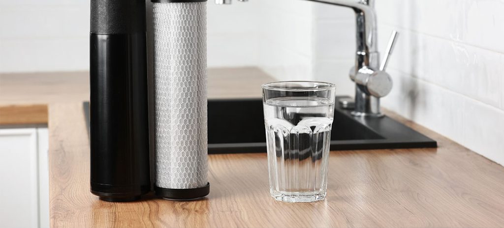 clean fresh water and set of filter cartridges on wooden table in a kitchen interior